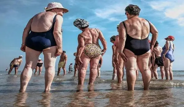 Grupo de pessoas idosas se exercitando na beira de uma praia: o melhor destino para a terceira idade