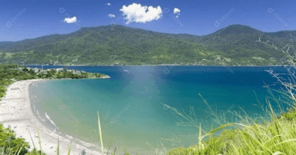 Imagem de Barequeçaba (São Sebastião) com montanhas ao fundo e mar verde azulado no litoral  norte de SP