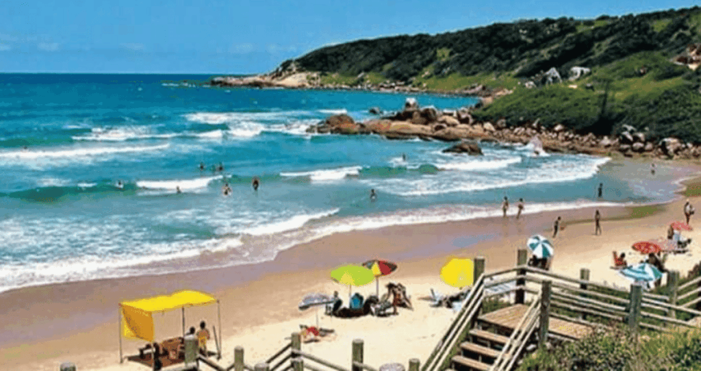 Imagem da praia do Rosa com pessoas na praia, um exemplo das melhores praias do Brasil