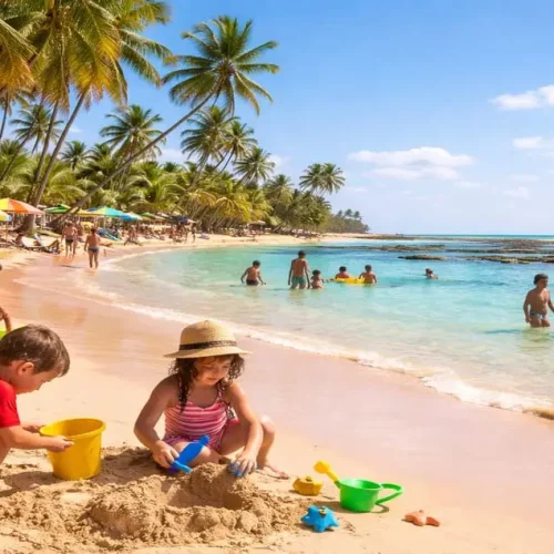 Crianças brincando na areia e no mar calmo em uma das melhores praias para crianças na Bahia, com águas rasas, palmeiras e famílias aproveitando o dia.