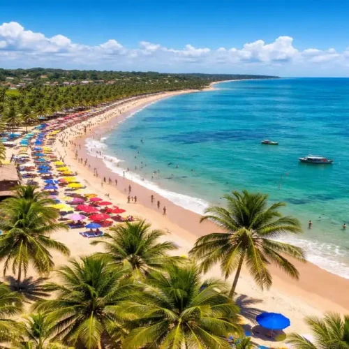 Praia de Porto Seguro, na Bahia, com mar azul-turquesa, coqueiros e faixa de areia movimentada em um dia ensolarado, um dos principais destinos turísticos do Brasil.
